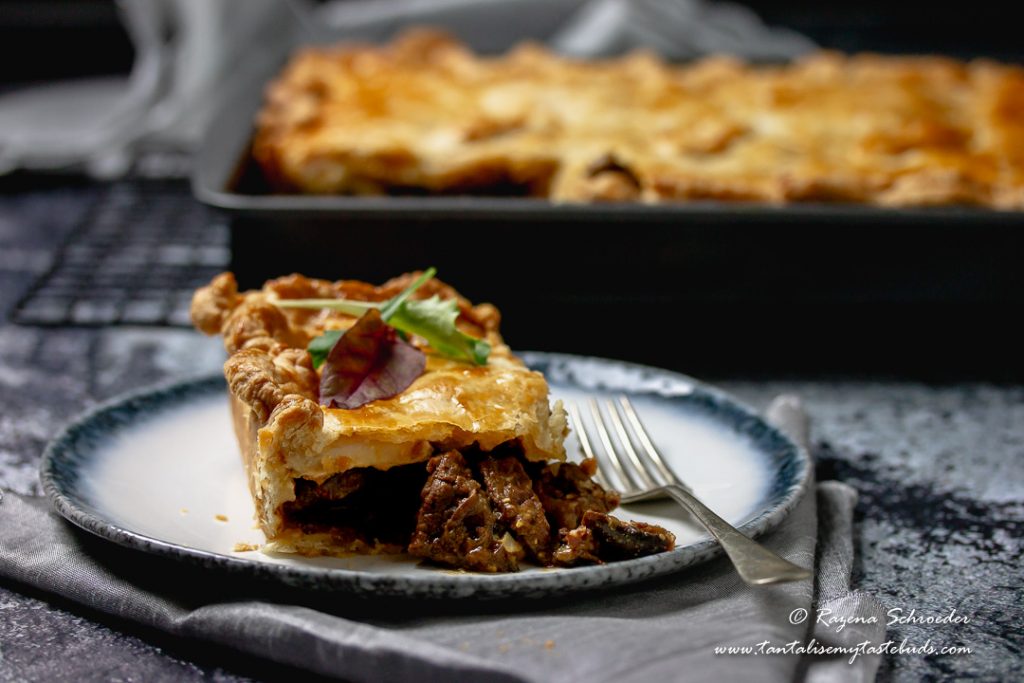 Slice of Cape Malay Pepper Steak Pie with pie tray in back